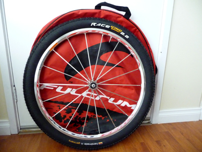 Picture of Fulcrum Red Metal Zero wheel mounted with Continental Race King 2.2 tyre and Fulcrum wheel bag in the background
